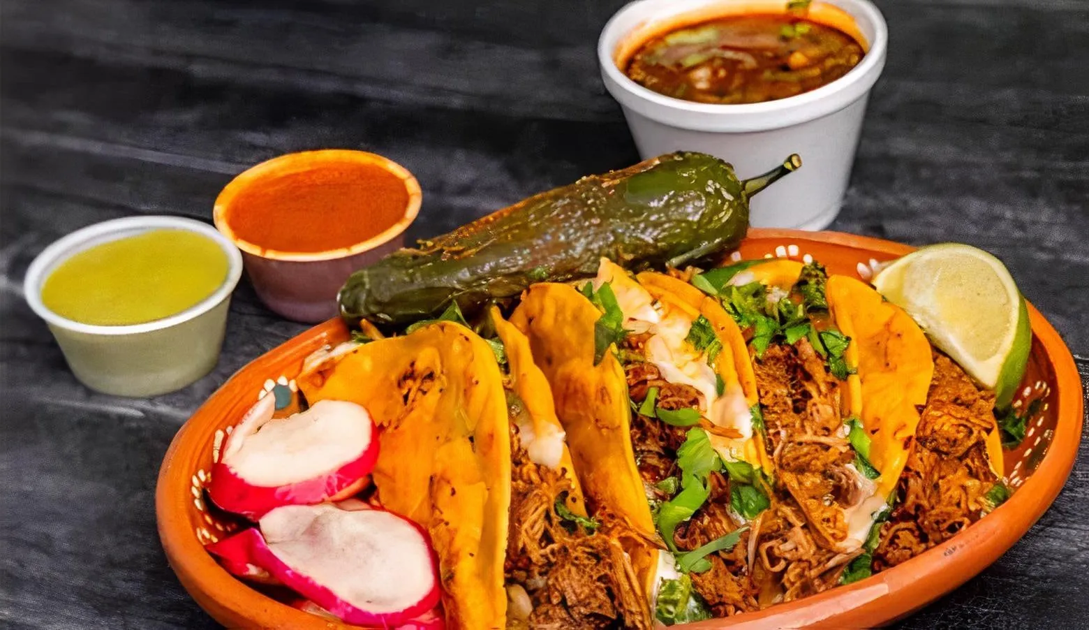 Birria tacos with a cup of consomé, grilled jalapeño and radish